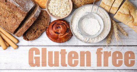 Téléchargez les photos : Différents produits sans gluten cuits au four et texte sur table en bois blanc, vue du dessus - en image libre de droit