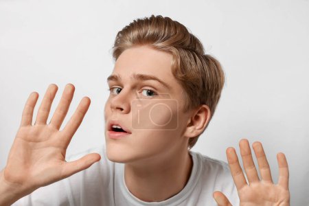 Téléchargez les photos : Shocked teenage boy stuck to transparent screen - en image libre de droit