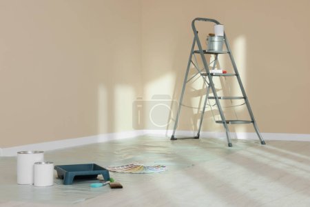 Foto de Herramientas de escalera y pintura cerca de la pared en habitación vacía, espacio para texto - Imagen libre de derechos