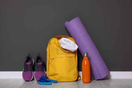 Rucksack und Sportausrüstung auf dem Boden in der Nähe der grauen Wand