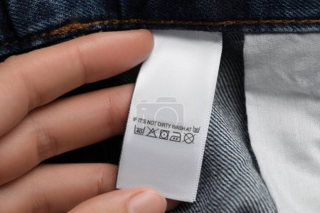 Téléchargez les photos : Femme tenant une étiquette de vêtements sur un jean vêtement, gros plan - en image libre de droit