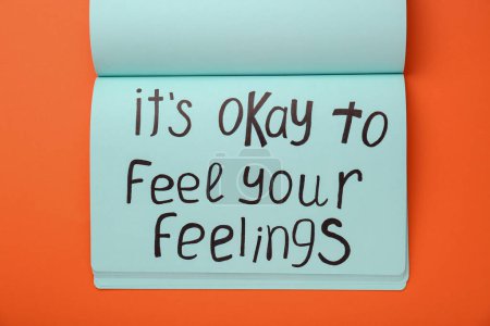 Téléchargez les photos : Carnet avec phrase It's Okay to Feel Your Feelings sur fond orange, vue du dessus - en image libre de droit