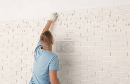 Photo for Professional builder installing new white decorative bricks on wall, back view - Royalty Free Image