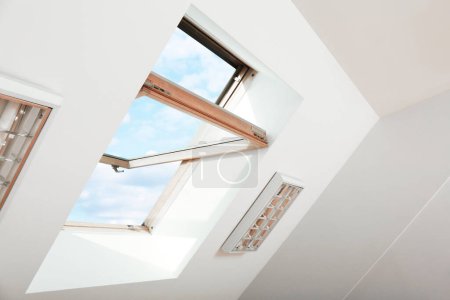 Foto de Ventana abierta del techo del tragaluz en el techo inclinado en la habitación del ático, vista de ángulo bajo - Imagen libre de derechos