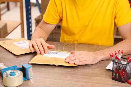 Postangestellte klebt Barcode auf Paket am Schalter drinnen, Nahaufnahme
