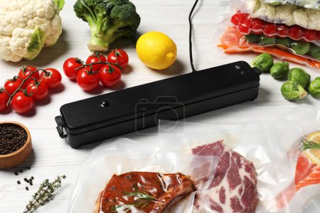 Vacuum packing sealer and different food products on white wooden table