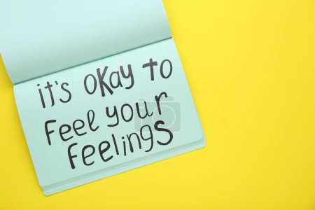 Téléchargez les photos : Notebook avec phrase It's Okay To Feel Your Feelings sur fond jaune, vue de dessus. Espace pour le texte - en image libre de droit