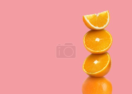 Foto de Corte apilado y naranjas enteras sobre fondo rosa, espacio para texto - Imagen libre de derechos