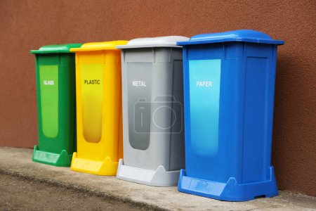 Foto de Muchos contenedores de reciclaje de color cerca de la pared marrón al aire libre - Imagen libre de derechos