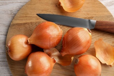 Photo for Tray with ripe onions and knife on wooden table, top view - Royalty Free Image