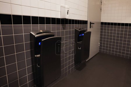 Photo for Modern hand dryers on tiled wall in public toilet - Royalty Free Image