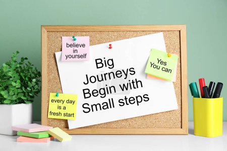 Corkboard with motivational quotes, potted houseplant and markers on white table-stock-photo
