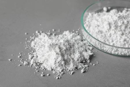 Petri dish and calcium carbonate powder on grey table