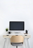 Cozy workspace with computer, houseplant and stationery on wooden desk at home Poster #644824044