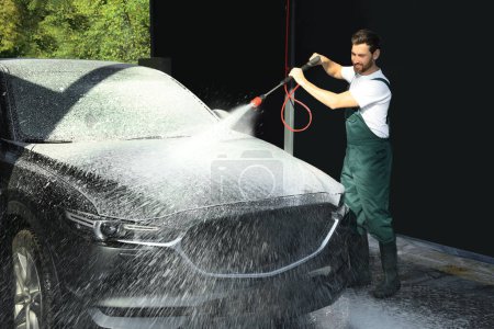 Téléchargez les photos : Travailleur lavage automatique avec jet d'eau haute pression au lavage de voiture extérieur - en image libre de droit