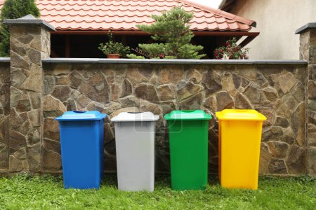Foto de Muchos contenedores de reciclaje de colores cerca de valla de piedra al aire libre - Imagen libre de derechos