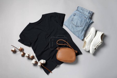 Foto de Camiseta con estilo, jeans y zapatillas de deporte sobre fondo gris claro, puesta plana - Imagen libre de derechos