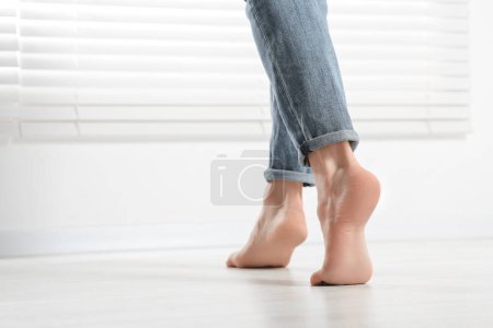 Photo for Barefoot woman walking on white parquet at home, closeup. Heated floor - Royalty Free Image