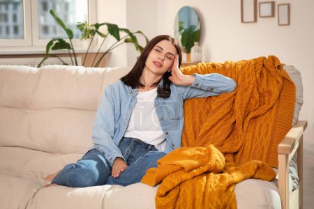 Téléchargez les photos : Jeune femme souffrant de maux de tête sur le canapé à la maison. Affections hormonales - en image libre de droit