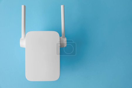 Photo for New modern Wi-Fi repeater on light blue background, top view. Space for text - Royalty Free Image