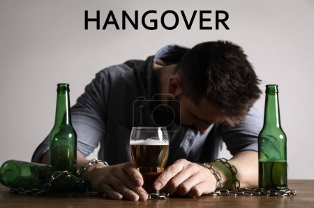 Photo for Suffering from hangover. Man chained to glass of beer at table - Royalty Free Image