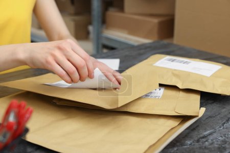 Foto de Trabajador de oficina de correos pegando código de barras en el paquete en el mostrador interior, primer plano - Imagen libre de derechos