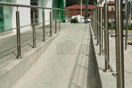 Concrete ramp with shiny metal railings outdoors