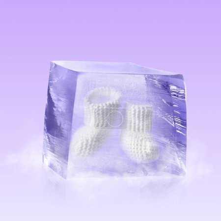 Photo for Conservation of genetic material. Knitted baby booties in ice cube as cryopreservation on violet background - Royalty Free Image
