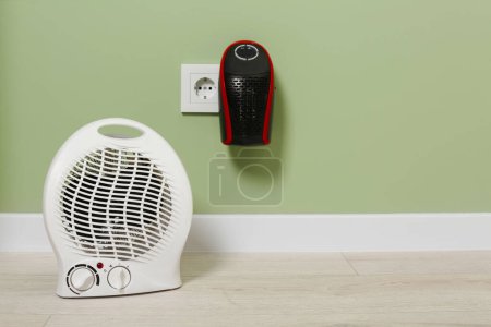 Photo for Different electric heaters near pale green wall indoors. Space for text - Royalty Free Image