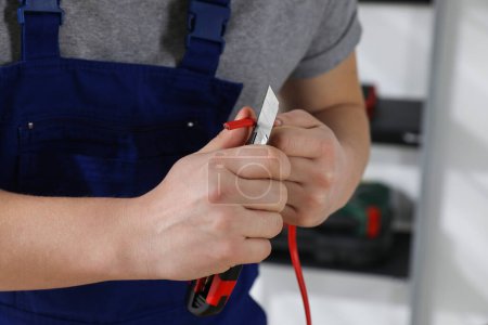 Foto de Electricista profesional en cableado de pelado uniforme en interiores, primer plano - Imagen libre de derechos