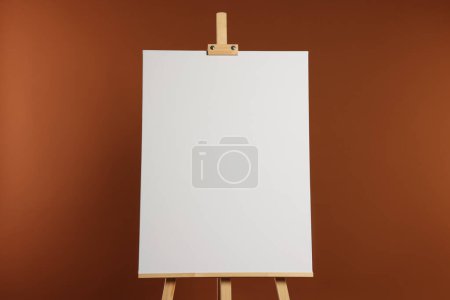 Photo for Wooden easel with blank canvas on brown background - Royalty Free Image