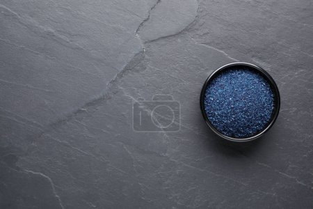 Téléchargez les photos : Bol de colorant alimentaire bleu sur table grise, vue de dessus. Espace pour le texte - en image libre de droit