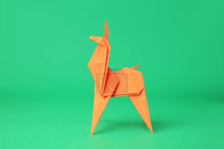 Foto de Arte en origami. Ciervo de papel naranja hecho a mano sobre fondo verde - Imagen libre de derechos