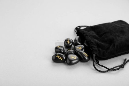 Tasche mit schwarzen Runensteinen auf hellgrauem Hintergrund, Platz für Text