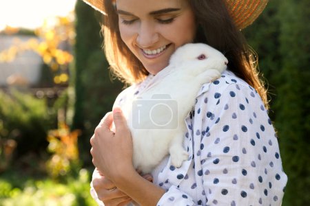 Mujer feliz con conejo lindo al aire libre en el día soleado, primer plano