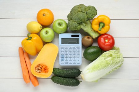Foto de Calculadora y productos alimenticios sobre mesa de madera blanca, puesta plana. Concepto de pérdida de peso - Imagen libre de derechos