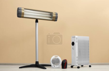 Photo for Different modern electric heaters on floor near beige wall indoors - Royalty Free Image