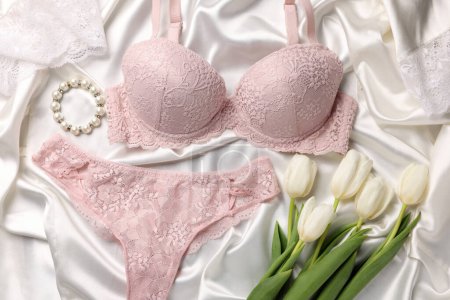 Téléchargez les photos : Composition à plat avec sous-vêtements pour femmes roses et tulipes sur tissu blanc - en image libre de droit