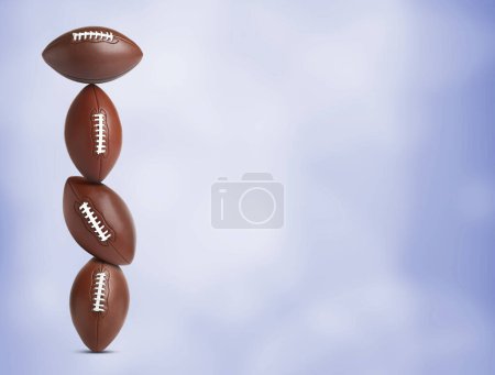 Téléchargez les photos : Empilement de ballons de football américains sur fond bleu. Espace pour le texte - en image libre de droit