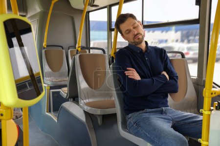 Müder Mann schläft während er in öffentlichen Verkehrsmitteln sitzt