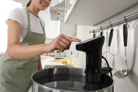 Mujer utilizando circulador de inmersión térmica en la cocina, primer plano. Sous vide cocinar