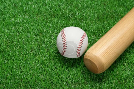 Foto de Bate de béisbol de madera y pelota en hierba verde, primer plano. Equipamiento deportivo - Imagen libre de derechos