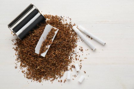 Flache Liegekomposition mit Walze und Tabak auf weißem Holztisch, Platz für Text. Handgedrehte Zigaretten herstellen