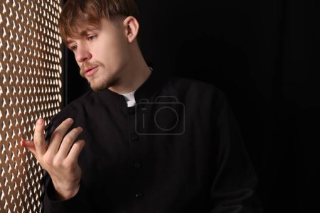 Foto de Sacerdote católico hablando con feligrés en cabina confesional - Imagen libre de derechos