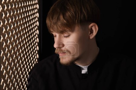 Téléchargez les photos : Prêtre catholique près d'une fenêtre en bois dans une cabine confessionnelle - en image libre de droit
