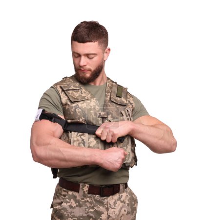 Foto de Soldado en uniforme militar aplicando torniquete médico en el brazo sobre fondo blanco - Imagen libre de derechos
