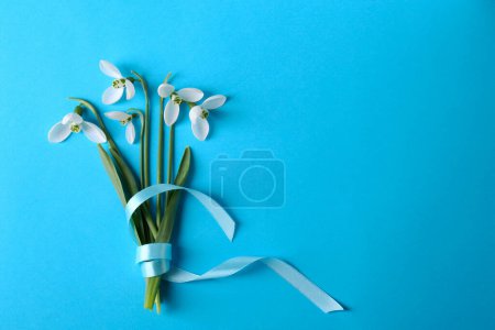 Photo for Beautiful snowdrops on light blue background, flat lay. Space for text - Royalty Free Image