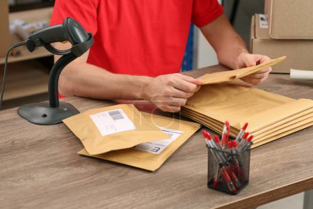 Téléchargez les photos : Post office worker with adhesive paper bags at counter indoors, closeup - en image libre de droit