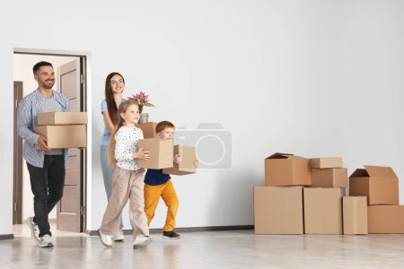 Famille heureuse avec des boîtes de déménagement entrant dans un nouvel appartement. S'installer dans la maison