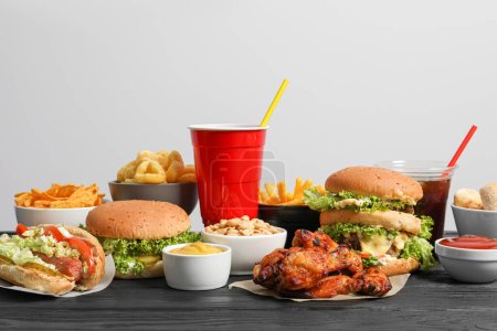 Foto de Papas fritas, hamburguesas y otras comidas rápidas sobre mesa de madera sobre fondo blanco - Imagen libre de derechos